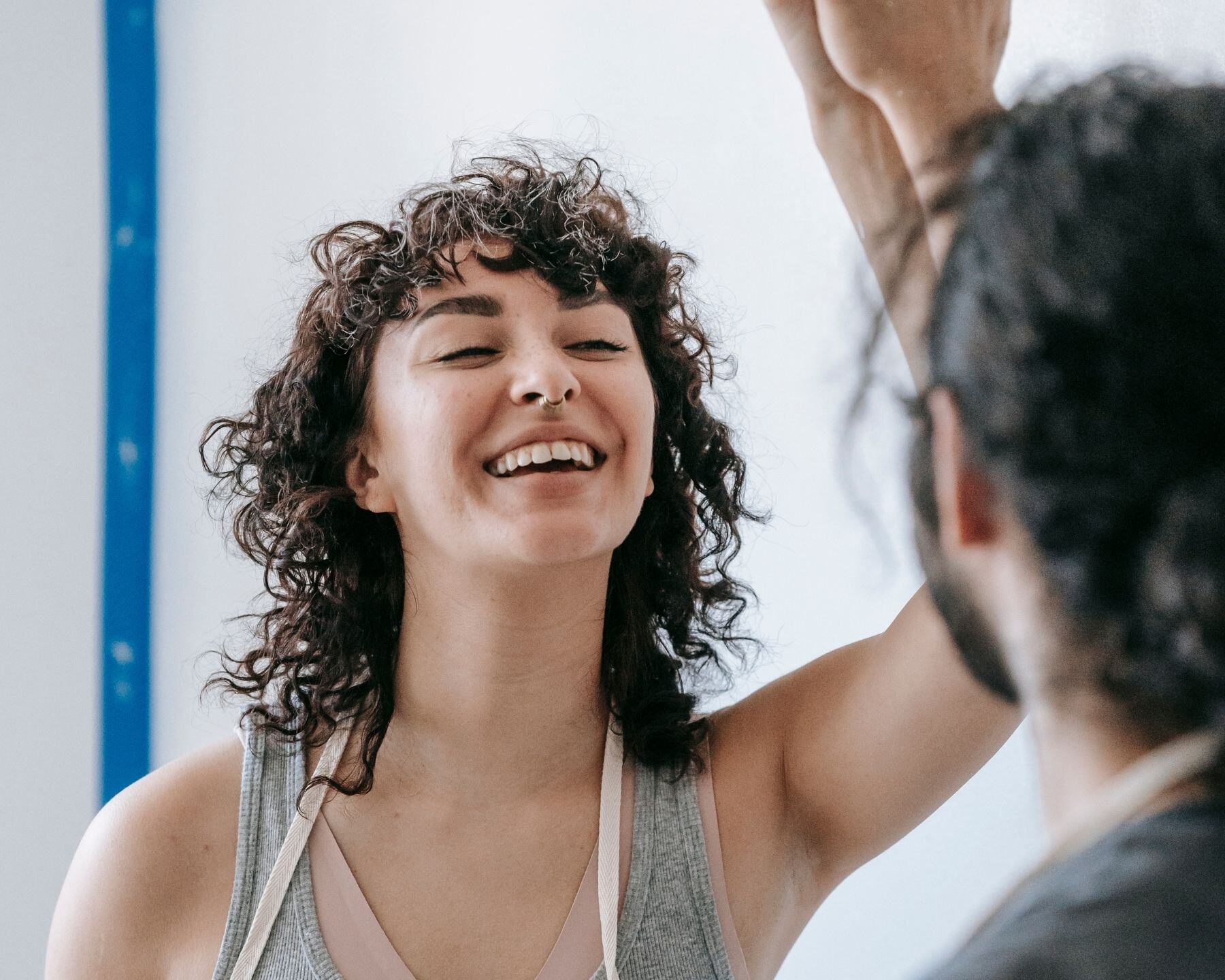 A woman with curly hair laughing with a friend