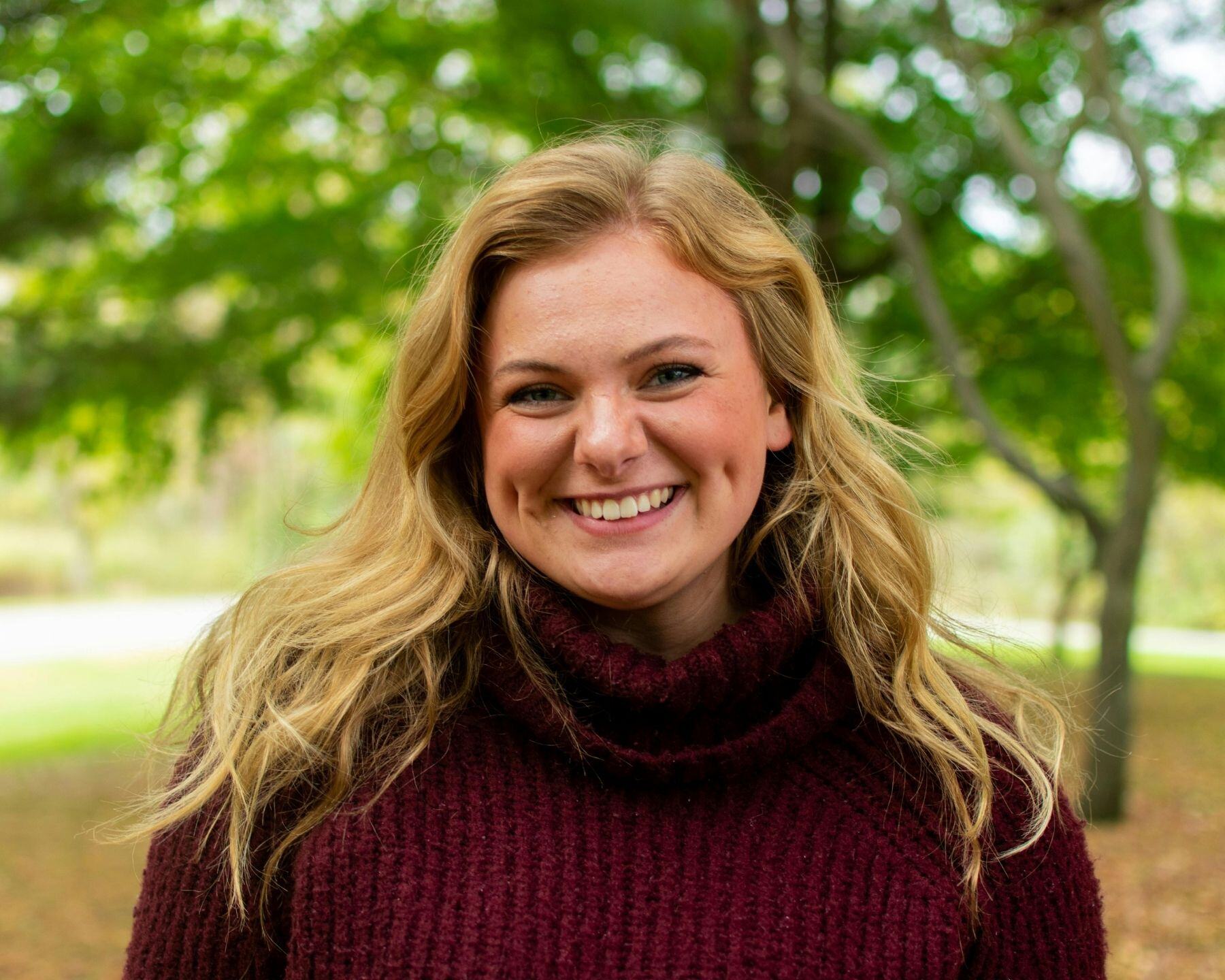 A woman smiling broadly in a park