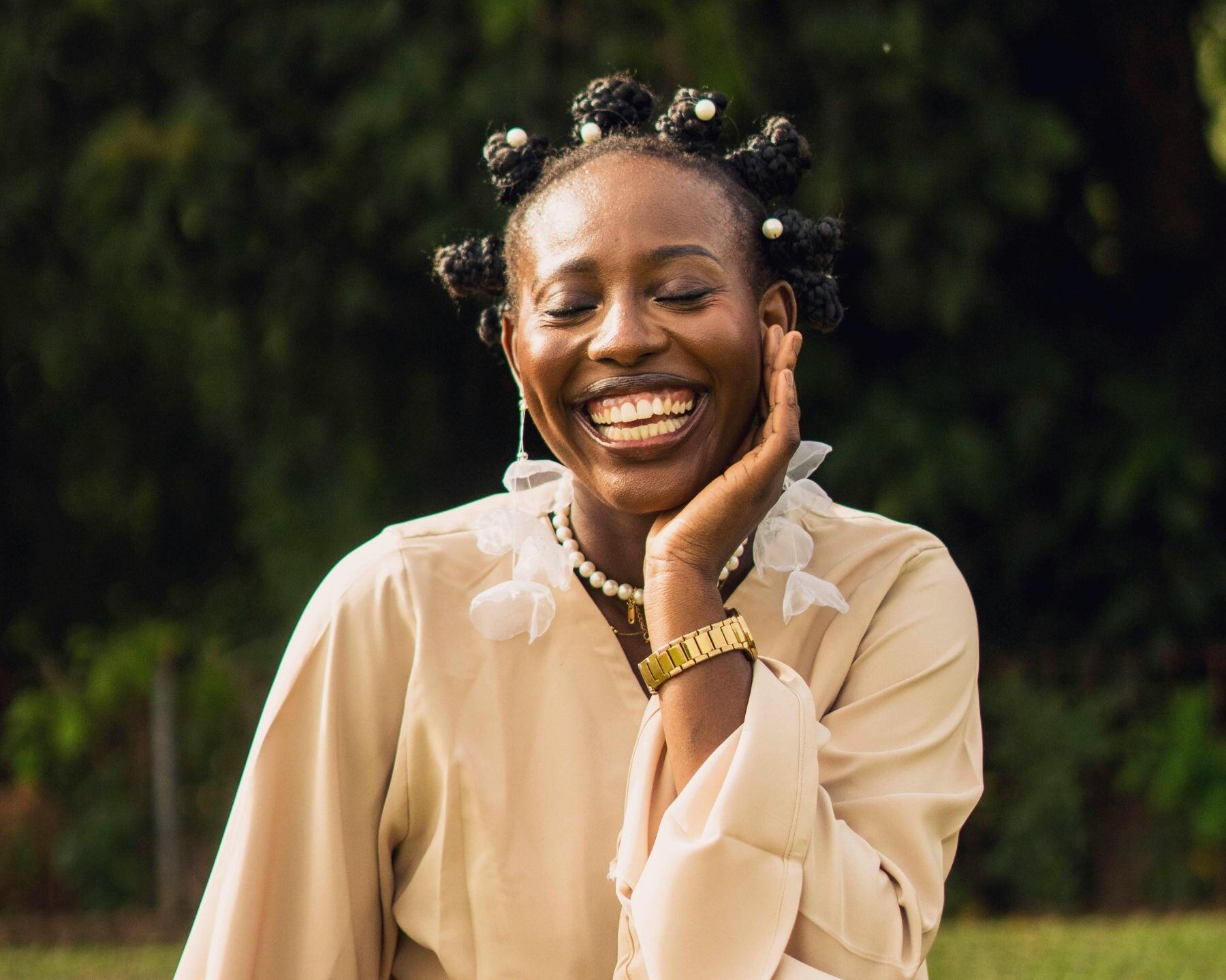 A woman laughing with her eyes closed, her hand on her cheek