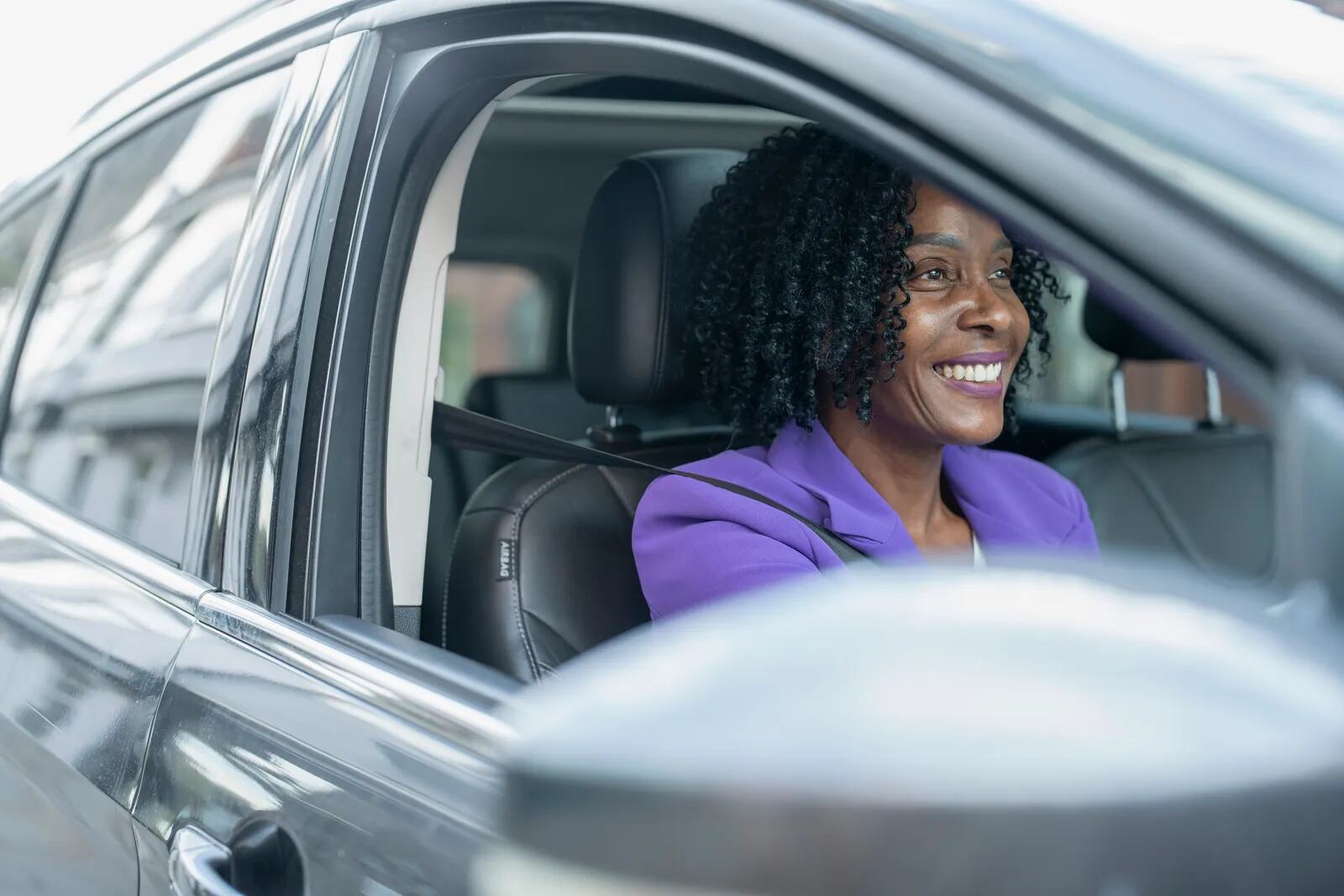 A woman smiling at the wheel of her car